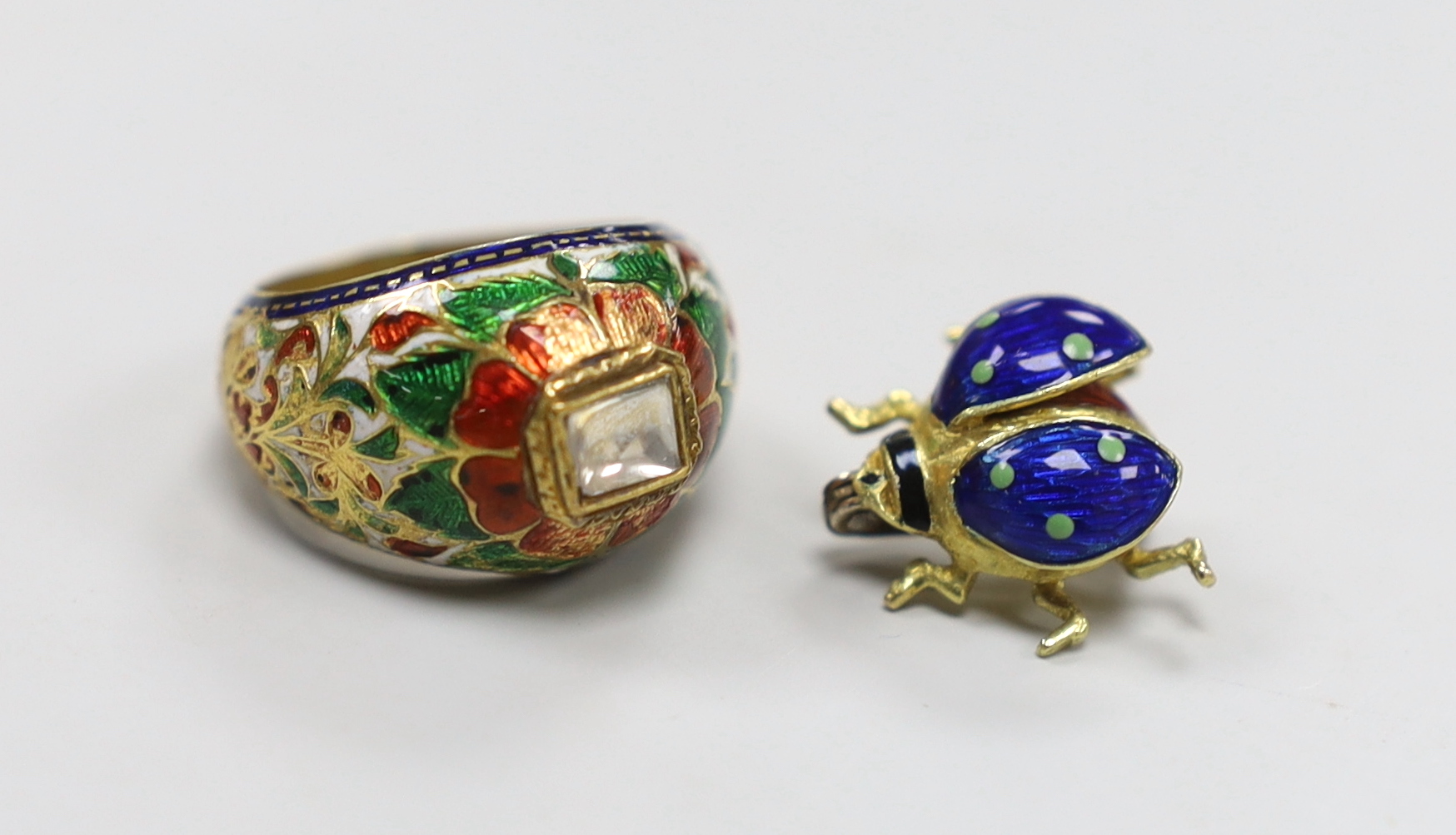A modern 18ct gold and three colour enamel set small bug brooch, 13mm, gross weight 3.1 grams and an Indian yellow metal, diamond and enamel set dress ring, gross weight 6 grams.